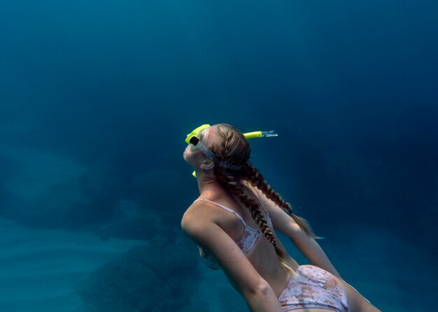 Mujer con equipo de buceo nadando en el océano