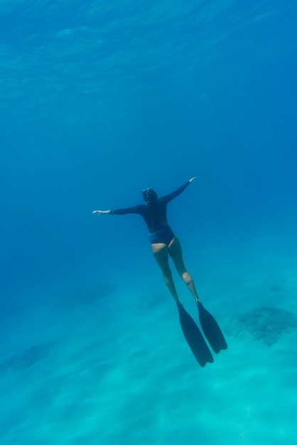 Mujer con equipo de buceo nadando en el océano