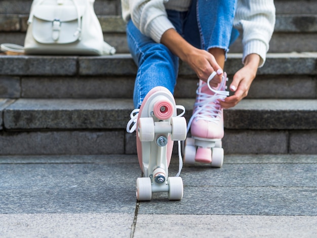 Mujer en las escaleras atar cordones de los zapatos en patines con mochila