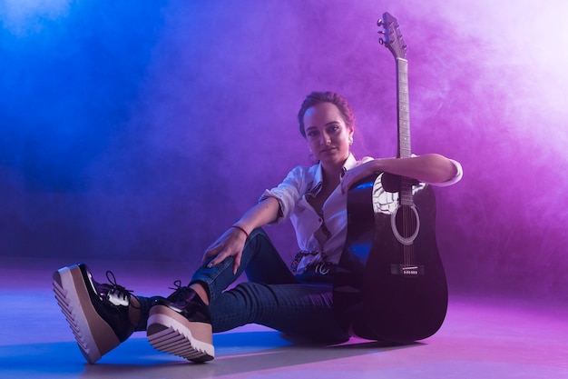 Mujer en el escenario con guitarra acústica