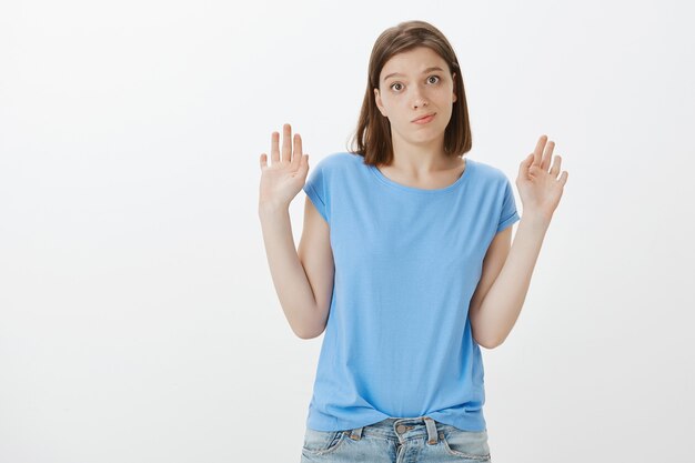Mujer escéptica despreocupada levantando las manos y mirando hacia otro lado, no está dispuesta a participar, no está involucrada