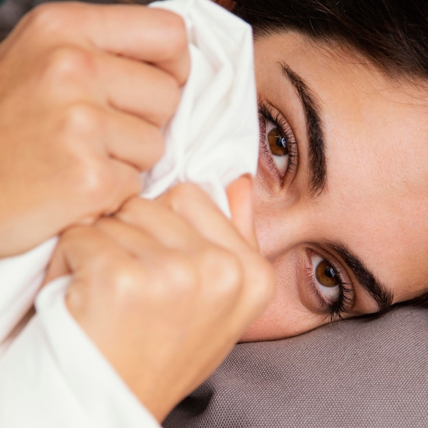 Mujer escondida debajo de las sábanas en casa