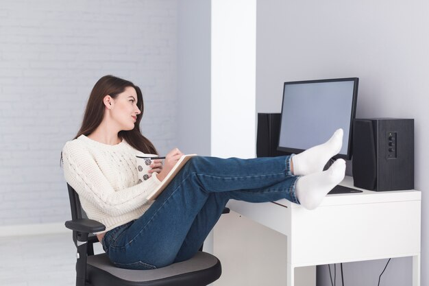 Mujer escribiendo en Bloc de notas en la computadora