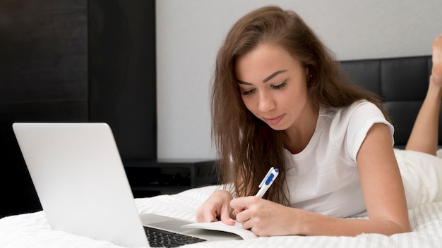 Mujer escribiendo en la cama