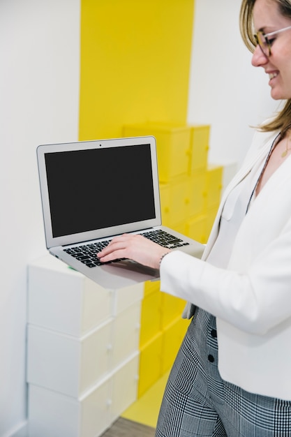 Mujer escribiendo en la computadora portátil y sonriendo