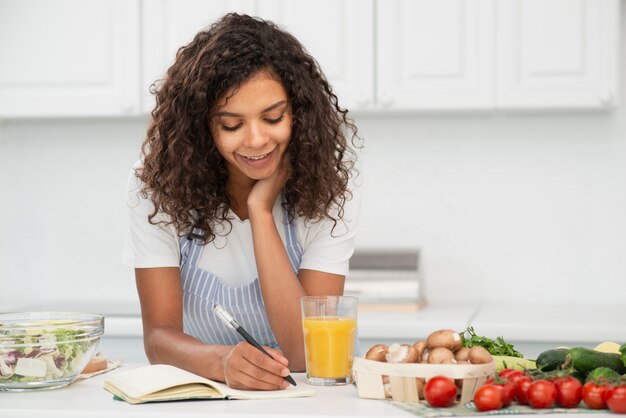 Mujer escribiendo en el cuaderno en la cocina