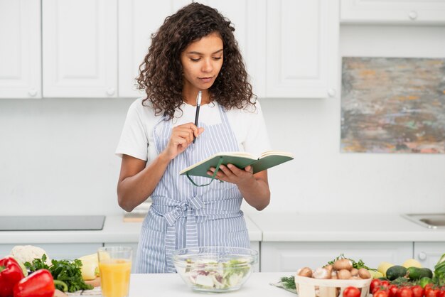 Mujer escribiendo en el cuaderno en la cocina