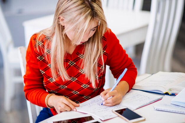 Mujer escribiendo en el cuaderno en la mesa