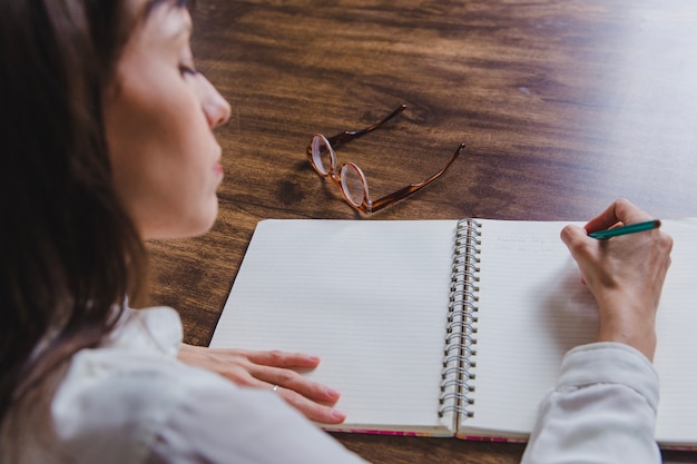 Mujer escribiendo en libro vista trasera