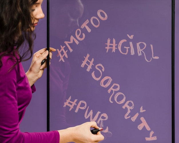 Foto gratuita mujer escribiendo palabras de género con hashtags en espejo