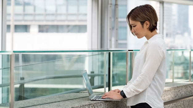 Foto gratuita mujer escribiendo en un portátil de tiro medio