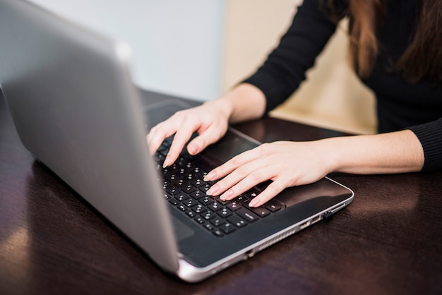 Mujer escribiendo en el teclado del ordenador portátil