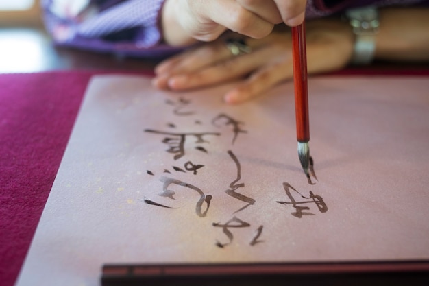 Mujer escribiendo con tinta sobre papel japonés