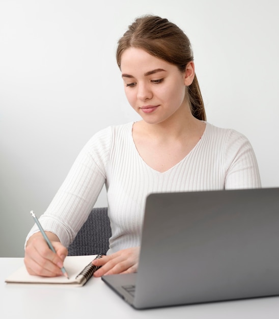 Foto gratuita mujer en el escritorio escribiendo en agenda