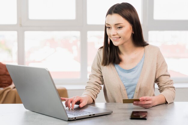 Mujer en el escritorio con laptop y tarjeta de crédito