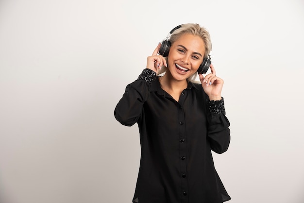 Mujer escuchando la canción con auriculares sobre fondo blanco. Foto de alta calidad