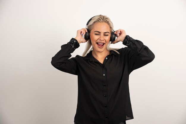 Mujer escuchando la canción con auriculares sobre fondo blanco. Foto de alta calidad