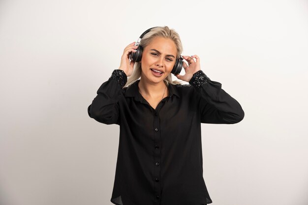 Mujer escuchando la canción con auriculares sobre fondo blanco. Foto de alta calidad