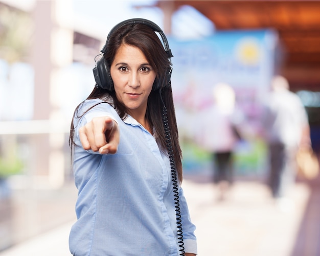 Mujer escuchando música con auriculares y señalando al frente
