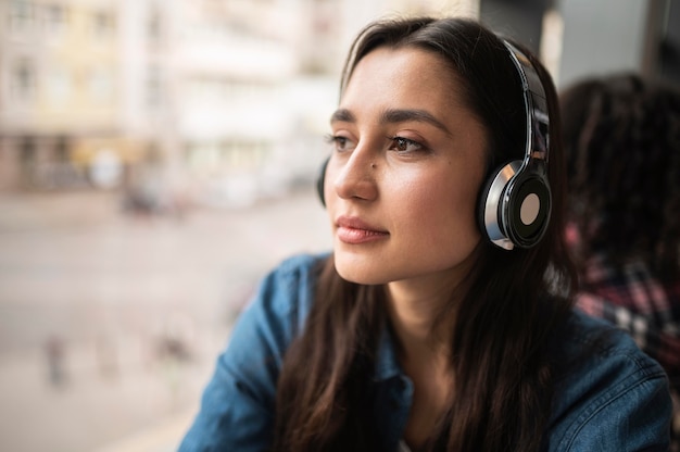 Mujer escuchando música en auriculares con su amiga en la parte de atrás