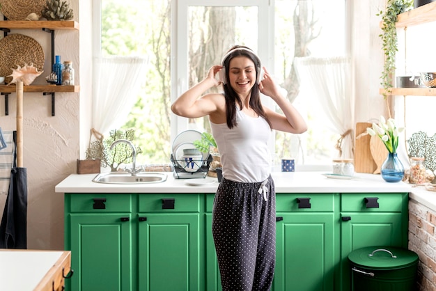 Mujer escuchando música en una cocina verde