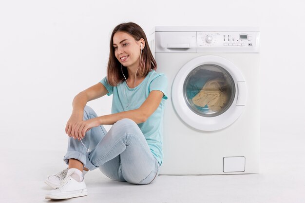 Mujer escuchando música y lavando la ropa