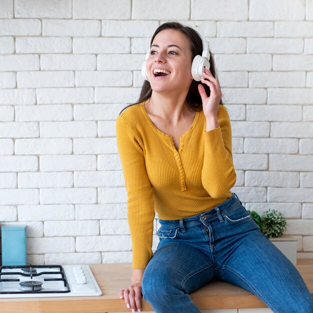 Mujer escuchando música y sentada en mostrador