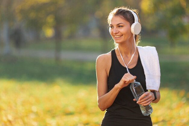 Mujer escuchando música y sosteniendo una botella de agua