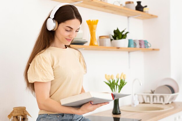 Mujer escuchando música a través de auriculares mientras lee