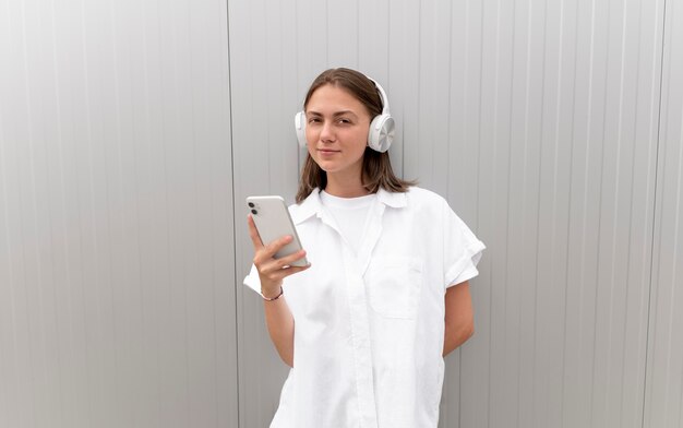 Mujer escuchando música a través de sus auriculares mientras sostiene su teléfono inteligente