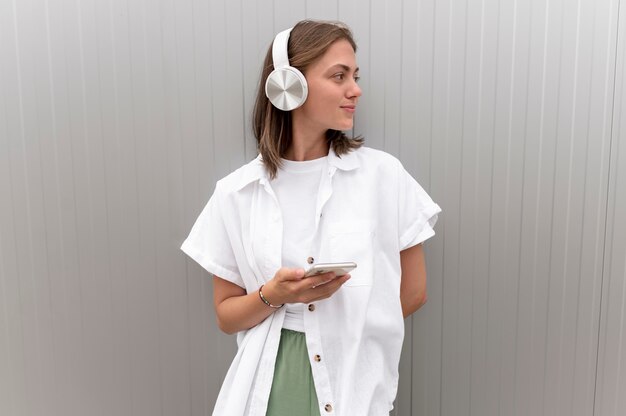 Mujer escuchando música a través de sus auriculares mientras sostiene su teléfono inteligente