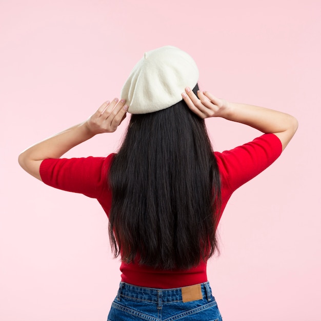 Foto gratuita mujer con espalda arreglando su sombrero