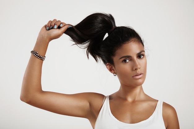 Mujer española sostiene su cabello en la mano mirando el concepto de fuerza del cabello de la cámara