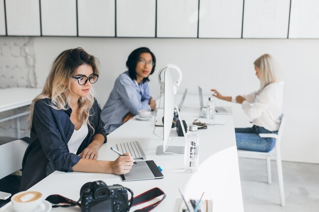 Mujer especialista en TI trabajando en un proyecto sentado en la oficina con colegas internacionales