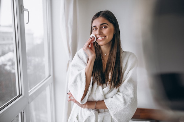 Mujer con espejo quitando maquillaje con almohadilla