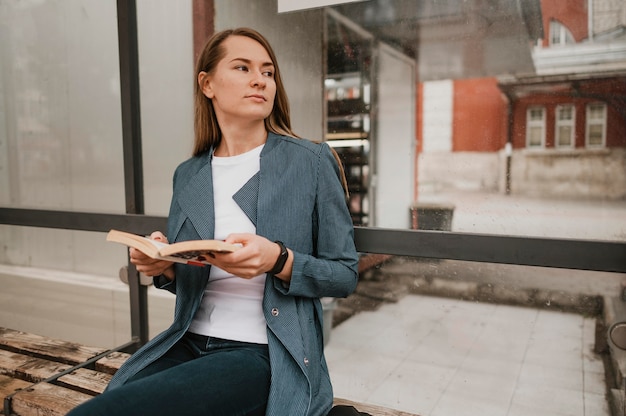 Foto gratuita mujer esperando el autobús y leyendo