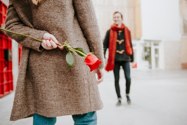 Mujer esperando hombre con rosa