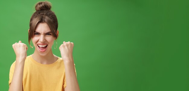 Mujer con espíritu de ganador levantando los puños apretados sonriendo emocionada y apoyando alentando siendo