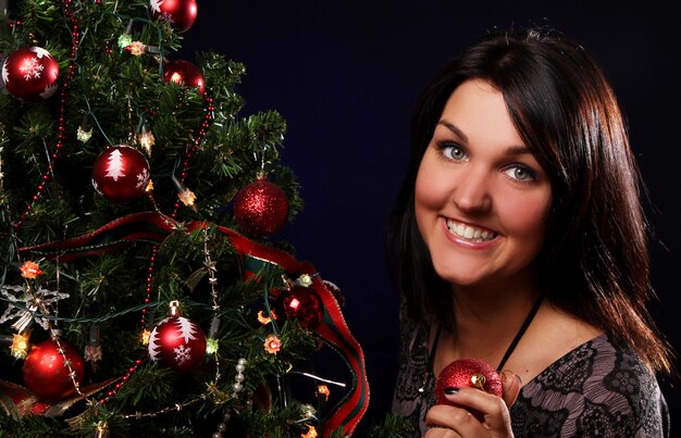 La mujer está decorando el árbol de navidad