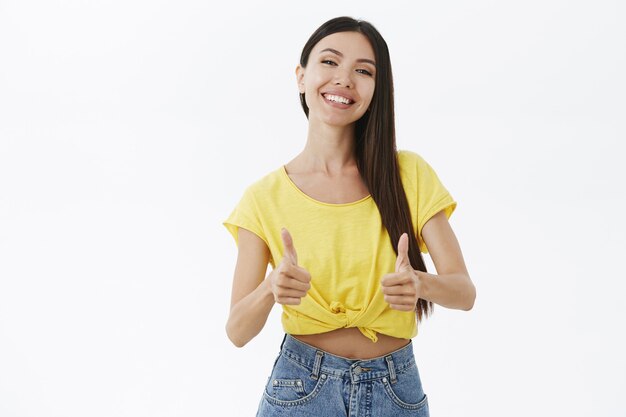 La mujer está encantada y feliz, escucha los consejos de un amigo mostrando los pulgares hacia arriba y sonriendo satisfecha