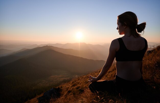 La mujer está meditando en la postura del loto en las montañas