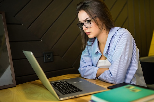 La mujer está trabajando en la computadora portátil en el cibercafé