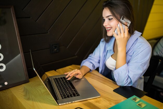 La mujer está trabajando en la computadora portátil y tiene una llamada