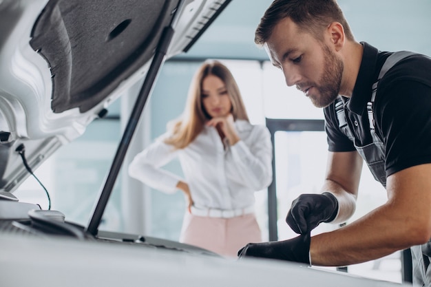 Mujer en la estación de servicio acr comprobando su coche con un mecánico