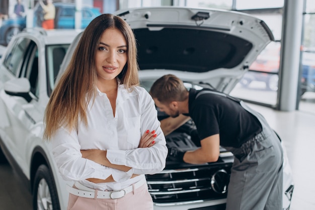 Mujer en la estación de servicio acr comprobando su coche con un mecánico