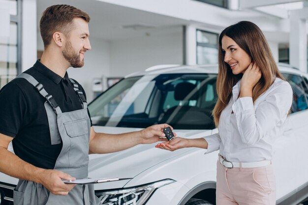 Mujer en la estación de servicio acr comprobando su coche con un mecánico