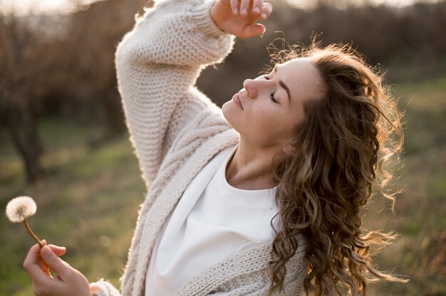 Mujer estar al aire libre y sosteniendo un diente de León