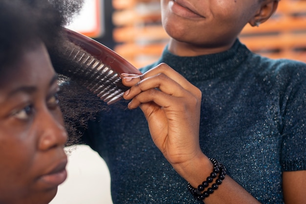 Mujer estilista cuidando el cabello afro de su cliente