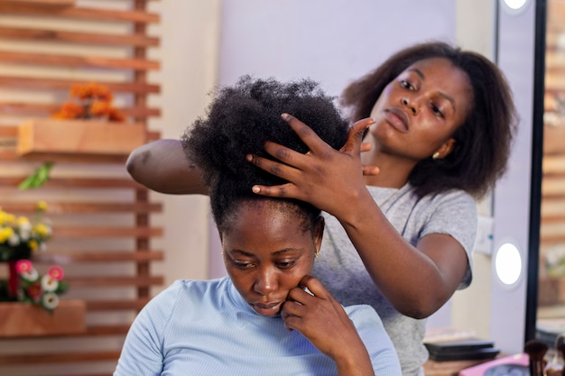 Mujer estilista cuidando el cabello afro de su cliente