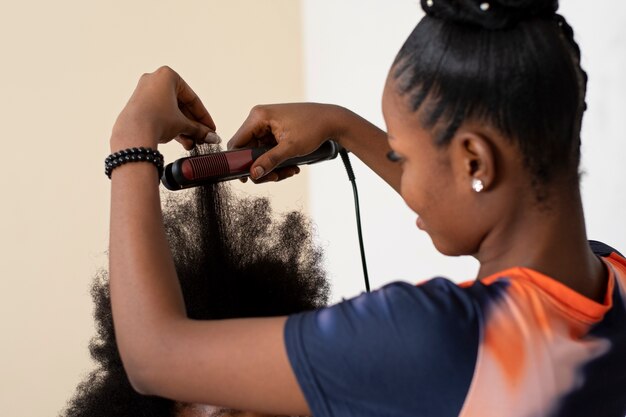 Mujer estilista cuidando el cabello afro de su cliente